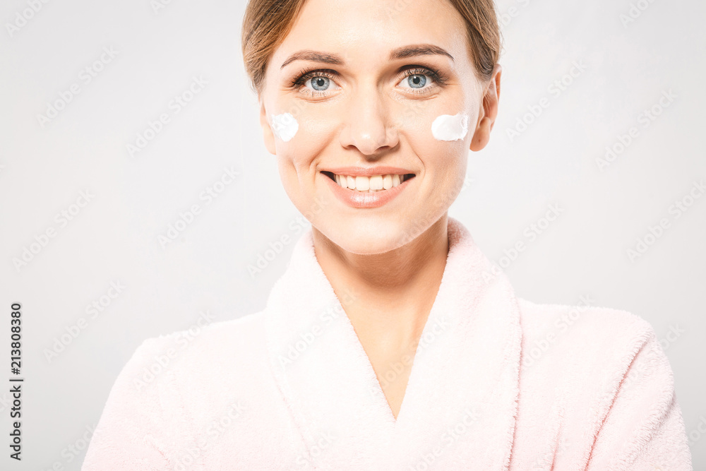 Portrait of young beautiful woman smiling while taking some facial cream isolated on white background with copy space. Portrait of young beautiful woman smiling while taking some facial cream isolated on white background with copy space.