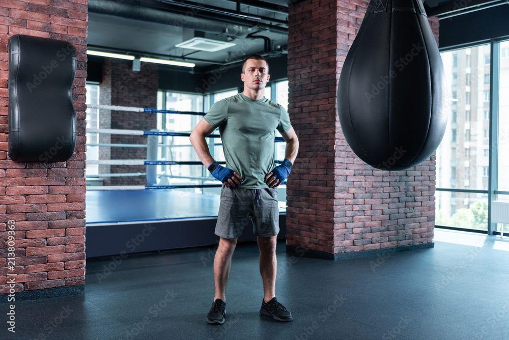 Self motivation. Dark-haired strong boxer wearing grey shorts and khaki shirt motivating himself before competition