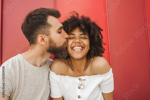 handsome young man kissing happy african american girlfriend