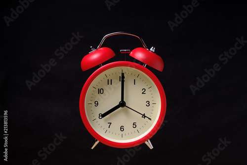 Red vintage alarm clock floating in the dark with blackboard background