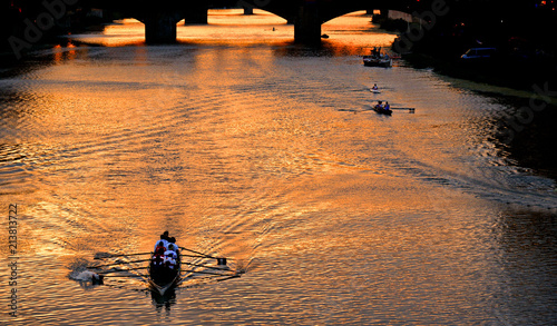 colorful buildings, bridge Ponte Vecchio and water reflections in warm sunset on river Arno with small boats in florence, italy