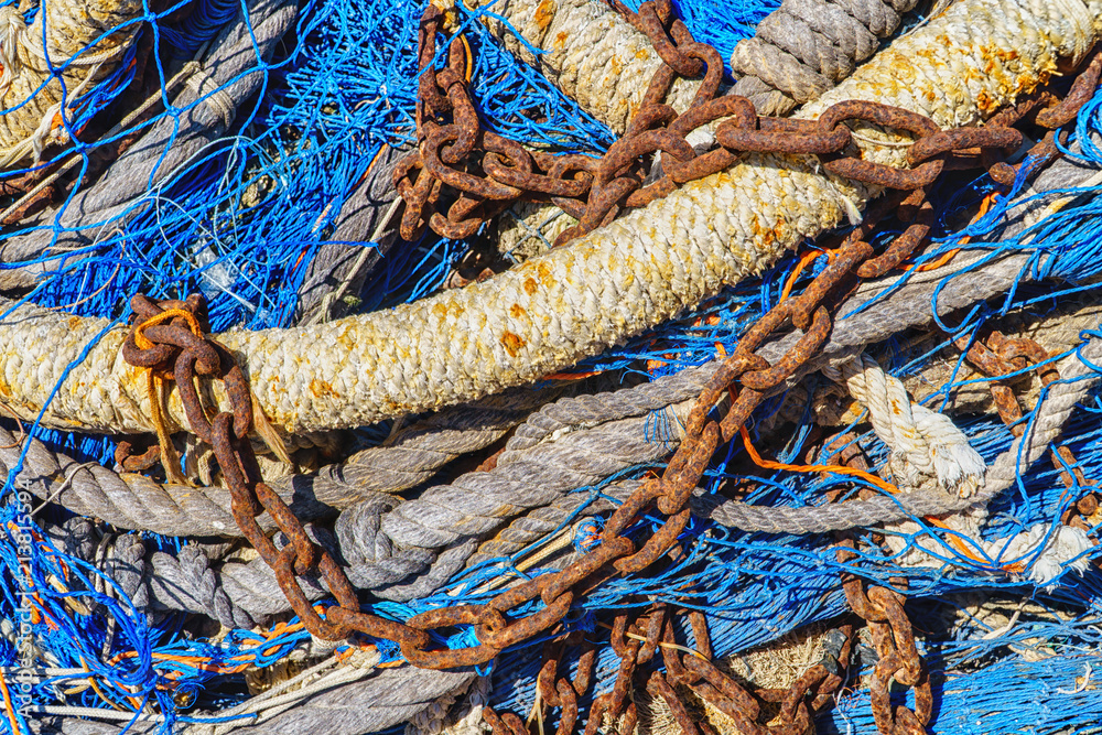 Old fishing nets with used ropes and a rusty chain