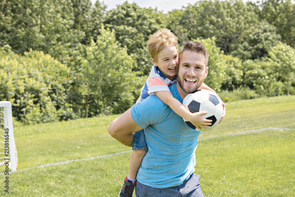 Man with child playing football outside on field Man with child playing football outside on field