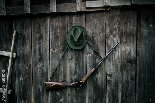 Professional hunters equipment for hunting. Rifle, hat, bag and others on a wooden black background.