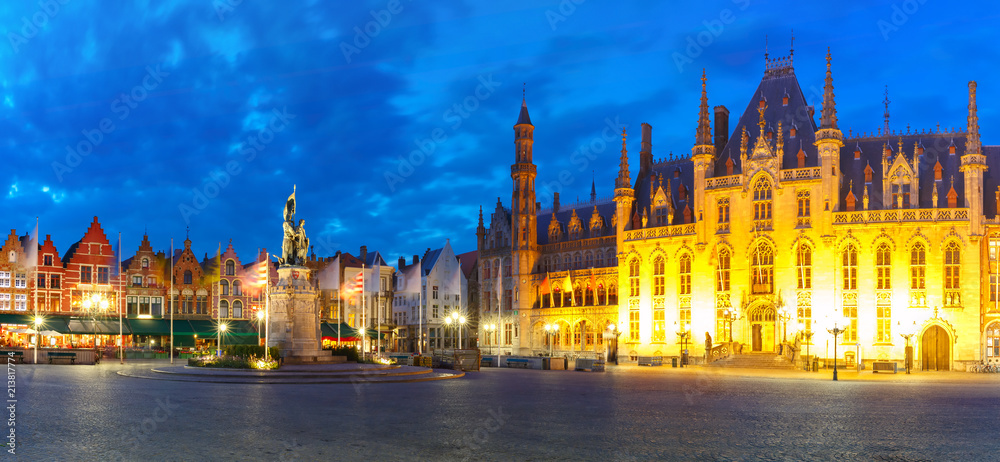 Panoramic view of typical Flemish colored houses and statue of Jan Breydel and Pieter de Coninck on the Grote Markt or Market Square during evening blue hour, Bruges, Belgium