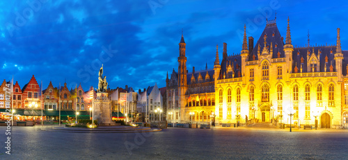 Panoramic view of typical Flemish colored houses and statue of Jan Breydel and Pieter de Coninck on the Grote Markt or Market Square during evening blue hour, Bruges, Belgium © Kavalenkava