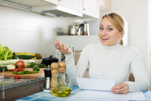 Happy housewife with documents in kitchen