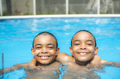 Portrait of twin brother boy having good time in swimming pool
