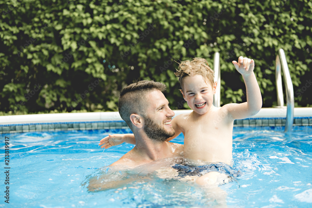 Cute little boy having fun with parents in pool
