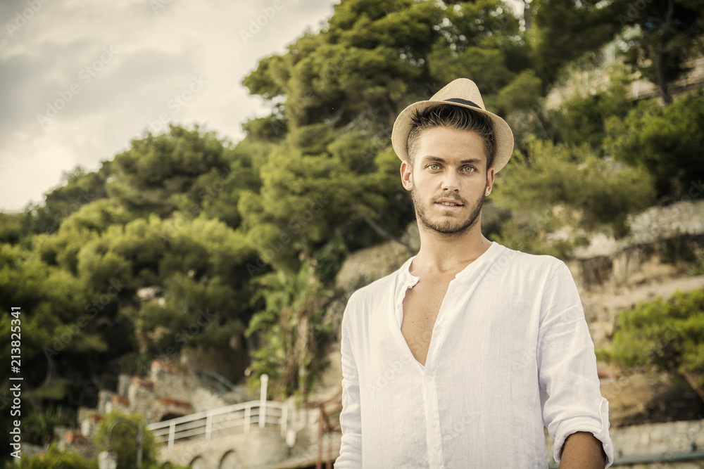 Handsome Young Man in Trendy Attire, Outdoor in Nature in a Sunny Summer Day Wearing a White Shirt Handsome Young Man in Trendy Attire, Outdoor in Nature in a Sunny Summer Day Wearing a White Shirt
