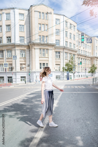 Summer sunny lifestyle fashion portrait of young stylish hipster woman walking on the street,