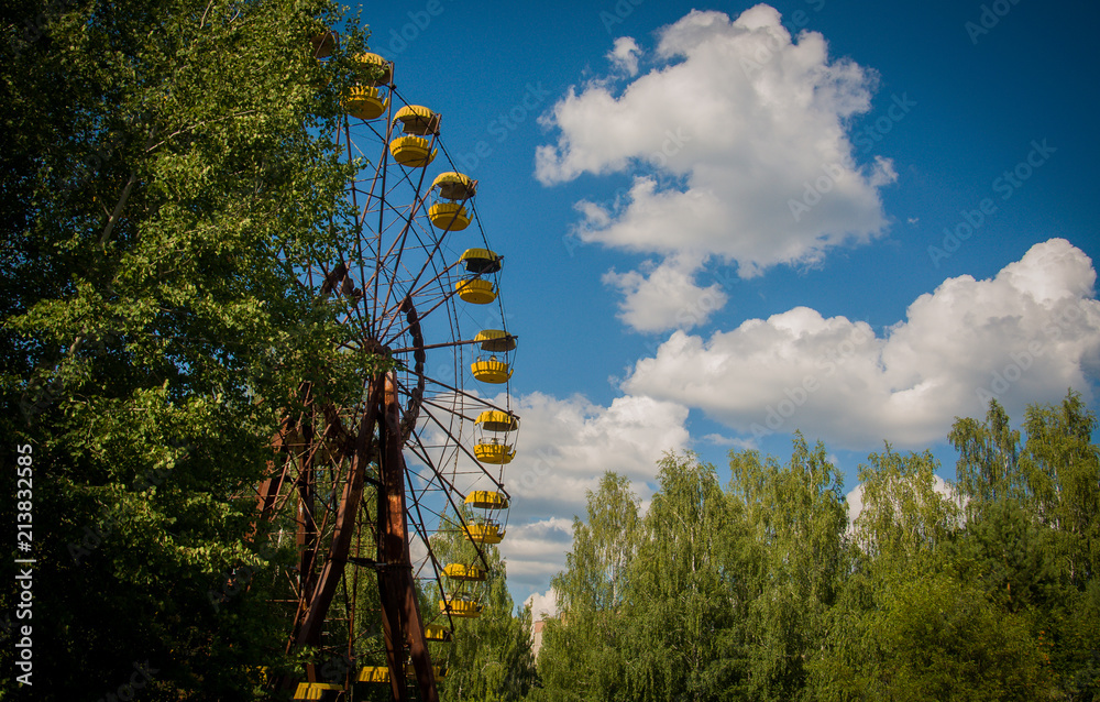 Famous yellow rusty Ferris wheel in the abandoned amusement park of the city of Pripyat in Chernobyl exclusion zone. Summer day in the radioactive city