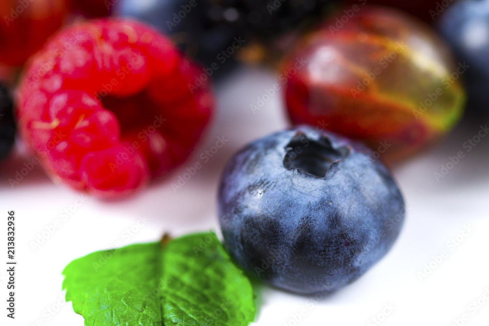 Close-up arrangement mixed, assorted berries including blackberries, strawberry, blueberry, raspberries and fresh leaf on white Close-up arrangement mixed, assorted berries including blackberries, strawberry, blueberry, raspberries and fresh leaf on white