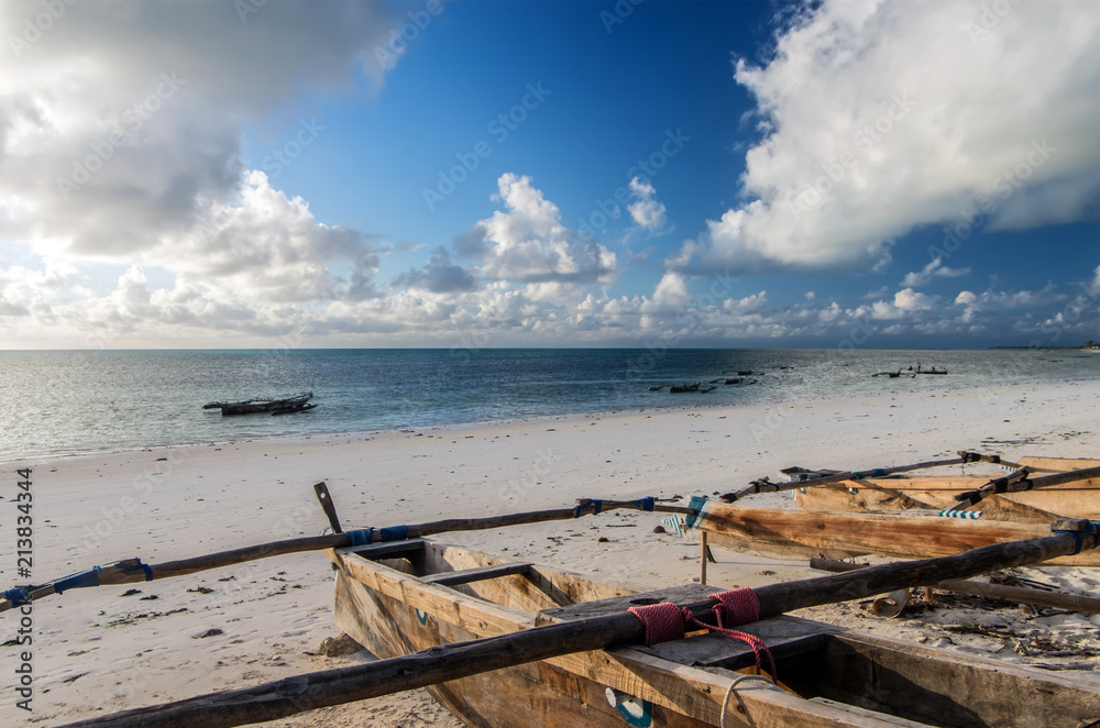 Traditional wooden fishing boats in the East of Zanzibar. Clouds over the Indian Ocean. Gorgeous sunrise over the ocean.