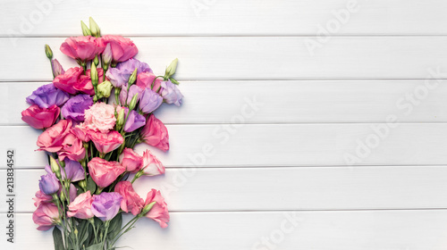 Beautiful bouquet of eustoma flowers on white wooden background. Copy space, top view,