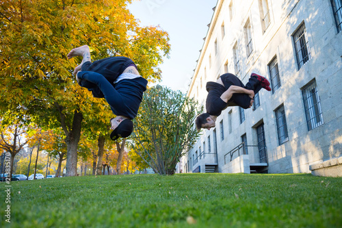 Εκτύπωση καμβά Two young men doing a side flip or somersault while they practicing parkour on the street