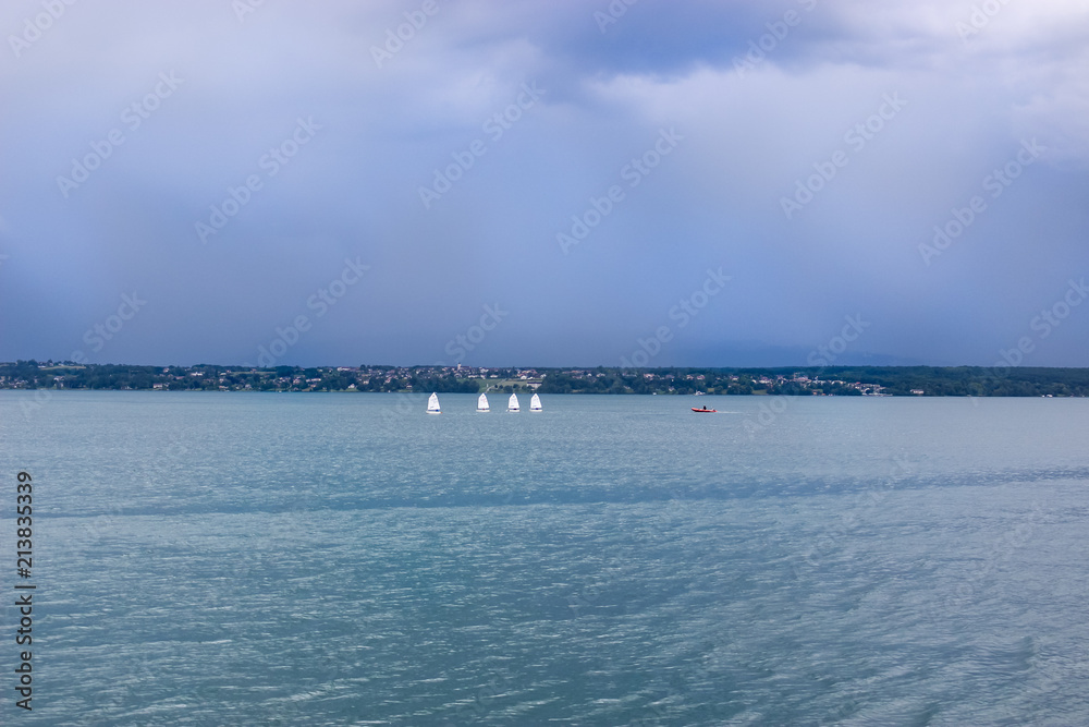 Row of sailboats in sea against sky