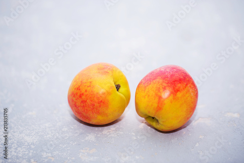Two ripe fresh nectarines on a gray background, close-up