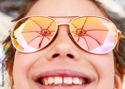 Beautiful young girl in sunglasses with beach umbrella. rerlection Holidays, travel, vacation and happiness concept.