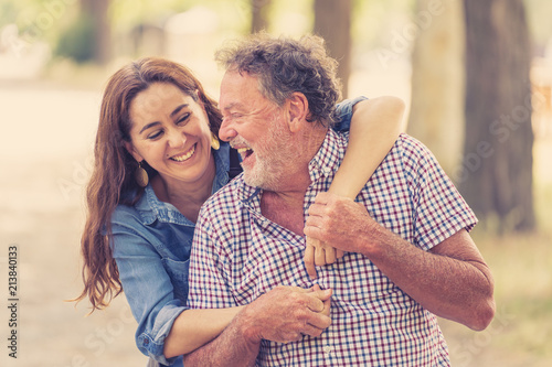 Happy daughter embracing her senior father from back in the park photo