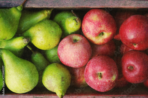 Ripe green pears and red apples in a wooden box with grunge texture, top view. Autumn harvest of pears