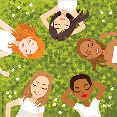 Five beautiful young multiracial women lying on green grass floor resting with eyes closed