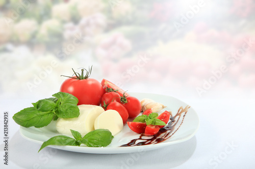 Mazzarella, pomidor, czosnek i bazylia na białym talerzu.
