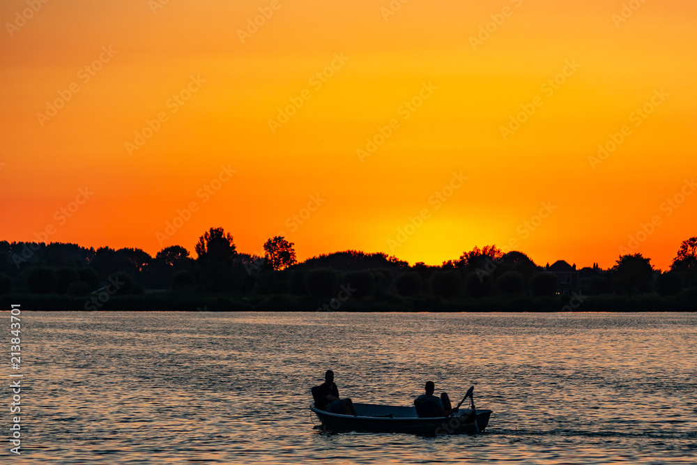 Fishermen in a small boat during sunset on lake Zoetermeerse plas