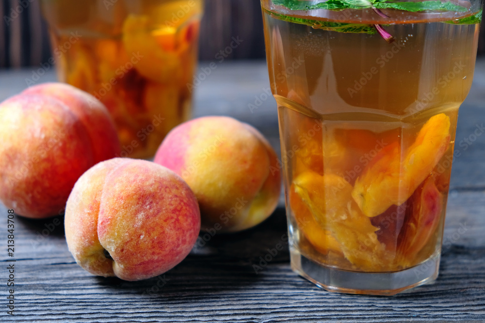 Peach ice tea in a glass with mint on wooden table Peach ice tea in a glass with mint on wooden table