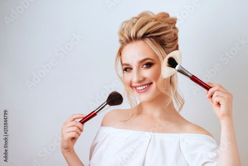 portrait of happy smiling blonde woman with long wavy hair style holding brush. photo