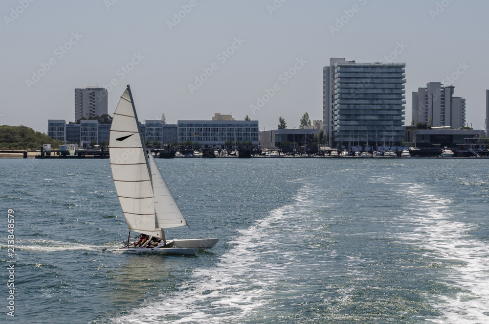 Naklejka premium embarcacion de recreo navegando frente al puerto deportivo de la Troia Portugal