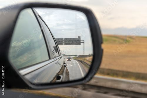 Asphalt road reflected in car mirror.