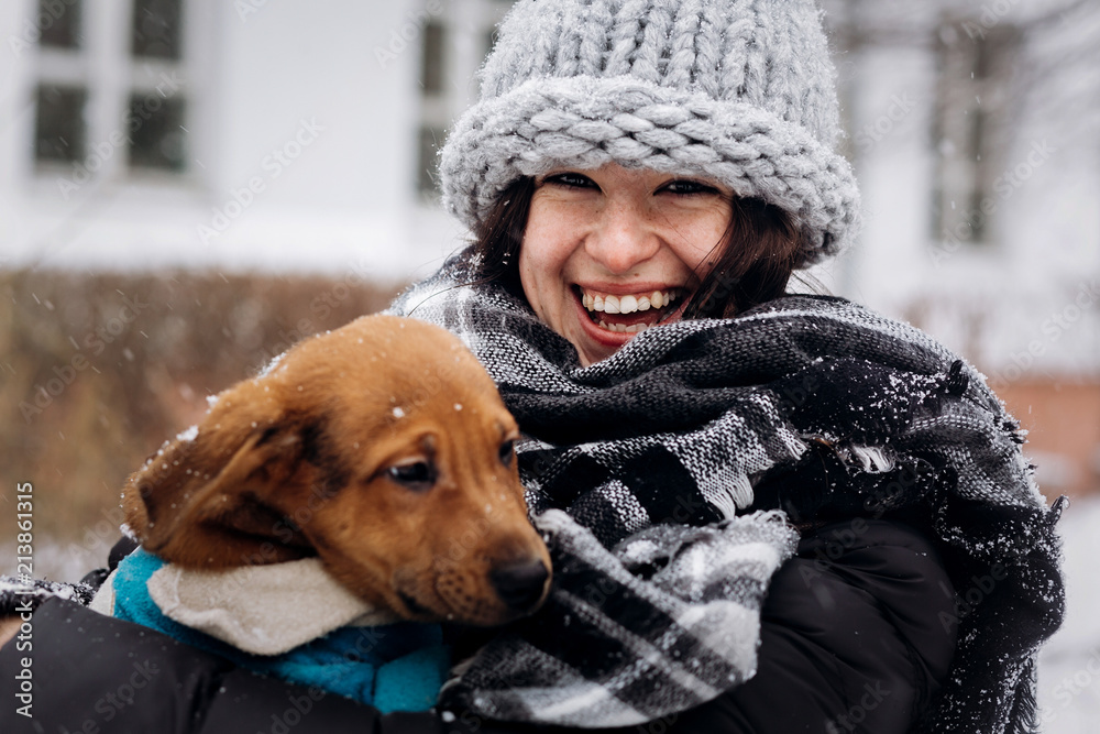 Φωτογραφία stylish hipster woman hugging and smiling cute puppy in snowy cold winter park