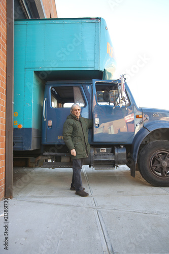 Moving company business owner smiling and standing in front of cargo truck in New York City, USA photo