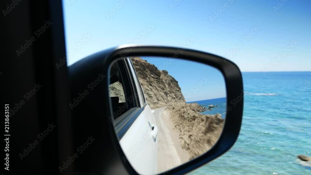 Driving along the sea side road and watching the coastline in the rear-view mirror