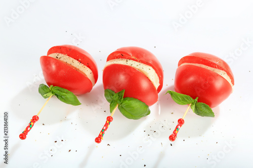 Mozzarella z pomidorem i bazylią nadziana na kolorową wykałaczkę posypana pieprzem.