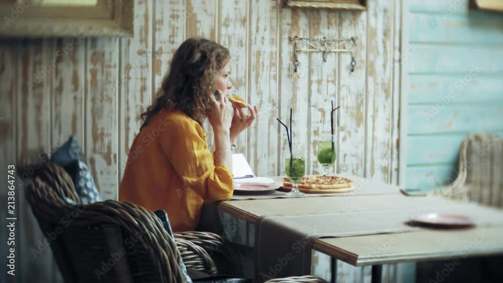 A young woman drinks a cocktail at a cafe bar and uses a telephone A young woman drinks a cocktail at a cafe bar and uses a telephone