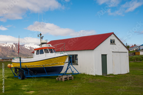 A small fishing boat on land outside a barn