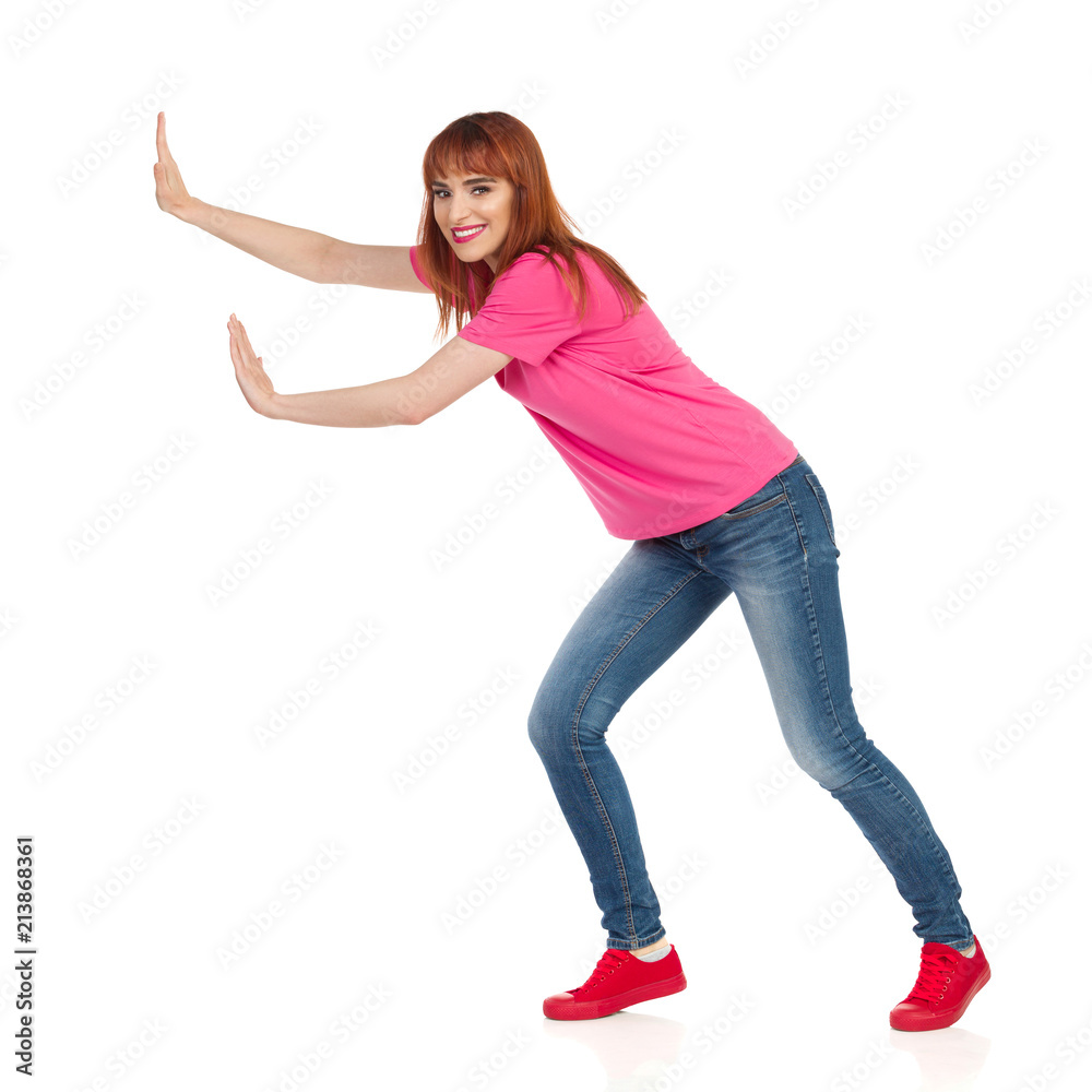 Side View Of Smiling Young Woman Pushing Something With Two Hands Side View Of Smiling Young Woman Pushing Something With Two Hands