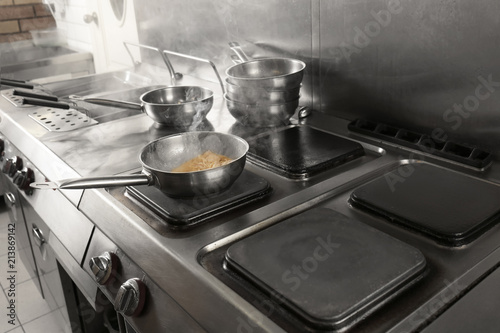 Cooking tasty pasta on stove in restaurant kitchen