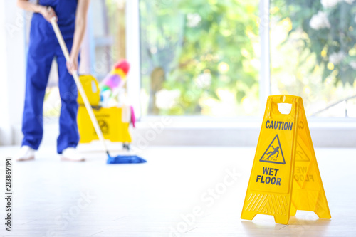 Slika na platnu Safety sign with phrase Caution wet floor and cleaner indoors