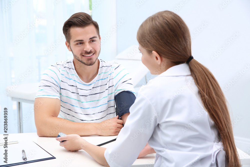 Obraz premium Doctor checking young man's pulse in hospital