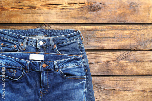 Blue jeans on wooden background, top view