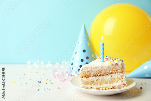 Slice of delicious birthday cake with candle on table