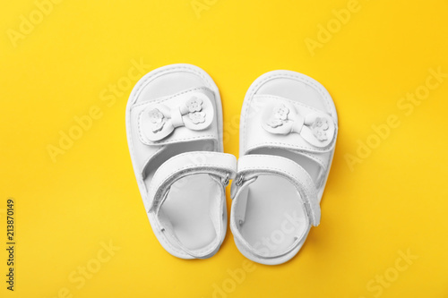 Pair of cute baby sandals on color background, top view