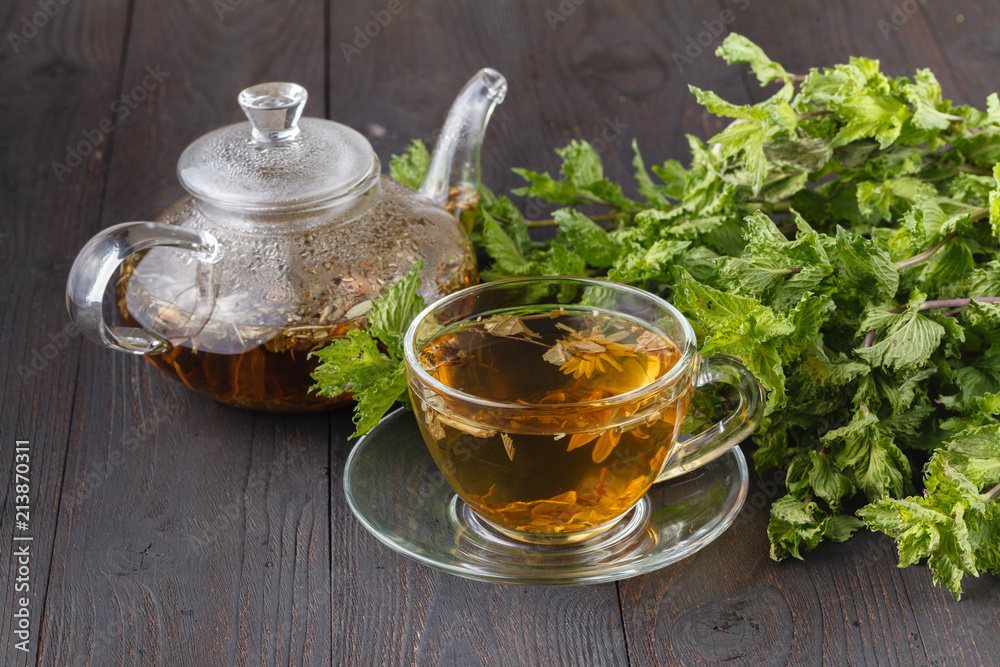 Cup of fresh herbal tea with mint on wooden table. Selective focus Cup of fresh herbal tea with mint on wooden table. Selective focus