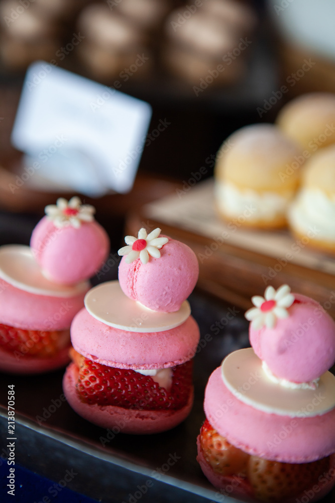 Cuteness overload, Delicious, mouthwatering and colorful Double Macarons filled with Fresh Summer Strawberry and cream, decorate with tiny flowers and white chocolate. Selective focus. Cuteness overload, Delicious, mouthwatering and colorful Double Macarons filled with Fresh Summer Strawberry and cream, decorate with tiny flowers and white chocolate. Selective focus.