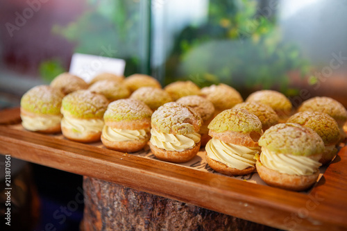 Tasty Mini Green Tea Choux au Craquelin or French Crunchy Cream Puff filled with delicious and creamy Chantilly Cream on a wooden tray. Selective focus. photo