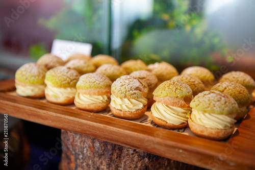 Fotografie Tasty Mini Green Tea Choux au Craquelin or French Crunchy Cream Puff filled with delicious and creamy Chantilly Cream on a wooden tray