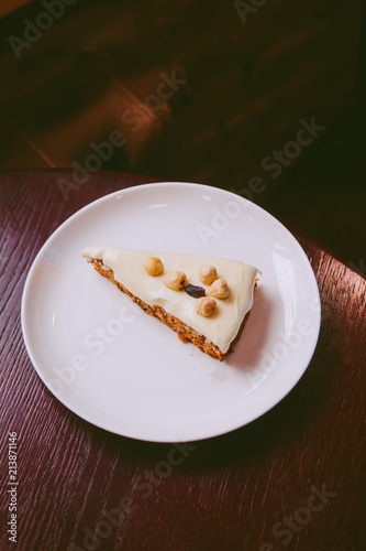 Raw vegan carrot cake with cashew cream layer from above on wooden table. Low key food photography styling concept. 